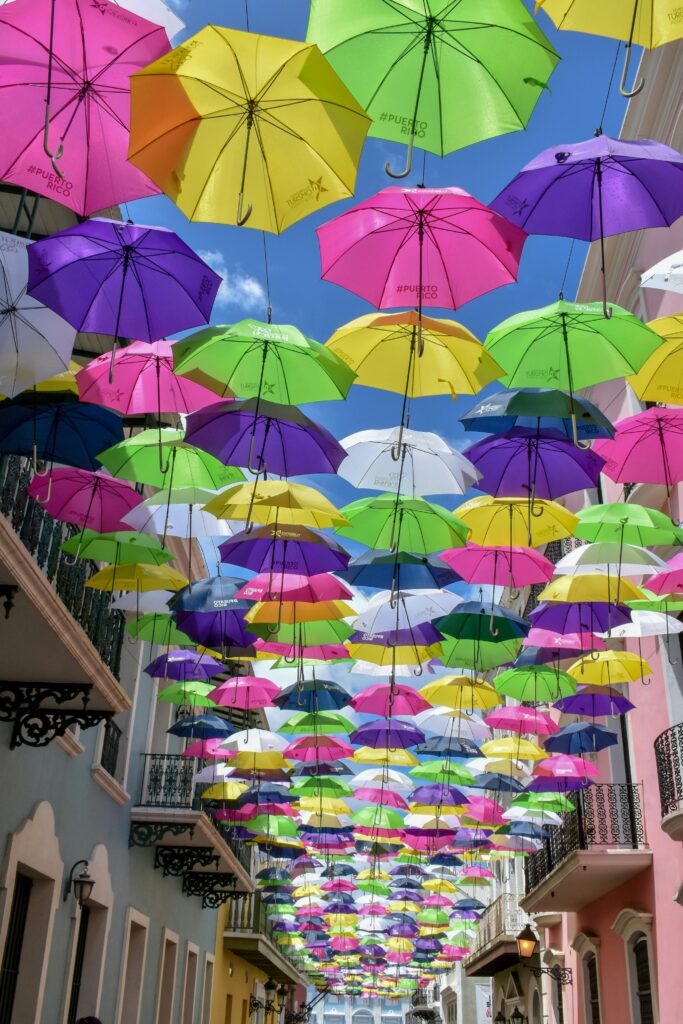 Colorful umbrellas hanging over a street create a vibrant and artistic atmosphere.